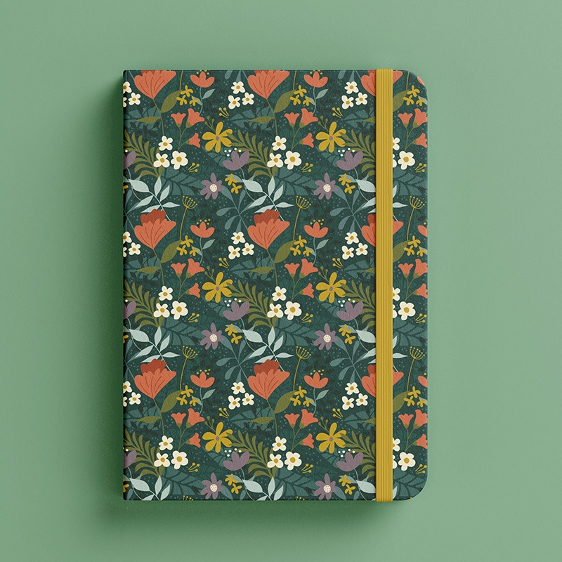 Carnet élégant couvert d'un motif fleuri vectoriel dans des tons verts foncés, rouges, jaunes et blancs, apportant une touche de fraîcheur et de couleur.